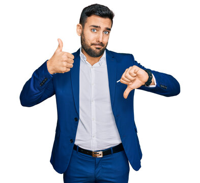 Young hispanic man wearing business jacket doing thumbs up and down, disagreement and agreement expression. crazy conflict