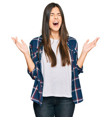 Young brunette woman wearing casual clothes celebrating mad and crazy for success with arms raised...