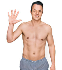 Fototapeta premium Handsome young man wearing swimwear shirtless showing and pointing up with fingers number five while smiling confident and happy.