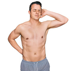 Fototapeta premium Handsome young man wearing swimwear shirtless suffering of neck ache injury, touching neck with hand, muscular pain