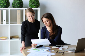 Two Businesswomen Analyzing Reports at Office Desk