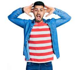 Young hispanic man with beard wearing casual denim jacket crazy and scared with hands on head, afraid and surprised of shock with open mouth