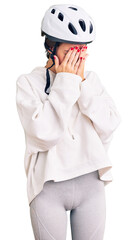 Beautiful brunette young woman wearing bike helmet and sporty clothes with sad expression covering face with hands while crying. depression concept.