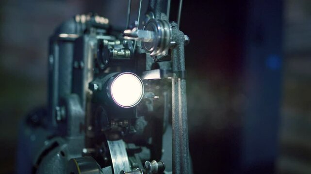 Close up on old projector shining it's light in darkness