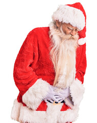 Old senior man with grey hair and long beard wearing traditional santa claus costume with hand on stomach because indigestion, painful illness feeling unwell. ache concept.