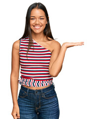 Beautiful hispanic woman wearing casual clothes smiling cheerful presenting and pointing with palm of hand looking at the camera.