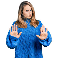 Young blonde woman wearing casual sweater moving away hands palms showing refusal and denial with...