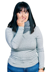 Young hispanic plus size woman wearing winter scarf looking stressed and nervous with hands on mouth biting nails. anxiety problem.