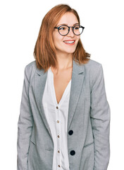 Young caucasian woman wearing business style and glasses looking away to side with smile on face,...