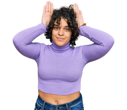Young hispanic woman with curly hair wearing casual clothes doing bunny ears gesture with hands palms looking cynical and skeptical. easter rabbit concept.