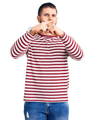 Young handsome man wearing striped sweater rejection expression crossing fingers doing negative sign