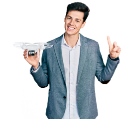 Young hispanic business man holding drone smiling with an idea or question pointing finger with happy face, number one