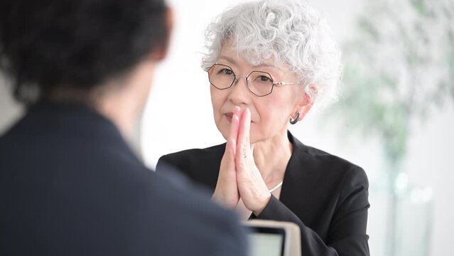 真剣な表情で打ち合わせするグレイヘアが素敵なシニア(高齢者)女性　営業などのビジネスシーンの動画