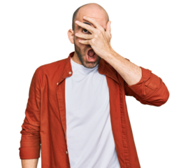 Young hispanic man wearing casual clothes peeking in shock covering face and eyes with hand, looking through fingers with embarrassed expression.