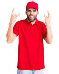 Young handsome man with beard wearing delivery uniform shouting with crazy expression doing rock symbol with hands up. music star. heavy music concept.