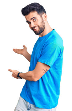 Young handsome man with beard wearing casual t-shirt inviting to enter smiling natural with open hand