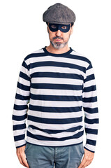 Middle age handsome man wearing burglar mask puffing cheeks with funny face. mouth inflated with air, crazy expression.