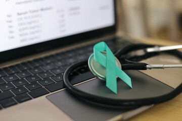 Teal Ribbon With Stethoscope On Laptop. The Teal Ribbon Is A Symbol Of Awareness And Support For Cervical Cancer Patients.