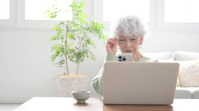 Smiling senior woman holding a smart phone (smartphone) Video of a senior woman with difficulty seeing her smartphone due to presbyopia