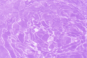 Purple water bubbles on the surface ripples. Defocus blurred transparent pink colored clear calm water surface texture with splash and bubbles. Water waves with shining pattern texture background