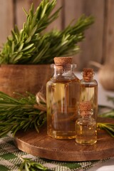 Essential oil in bottles and rosemary on table