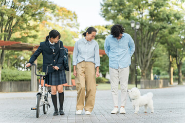 愛犬の散歩をする中学生・高校生と両親の家族・ファミリー（犬・ペット・娘・両親・3人）
