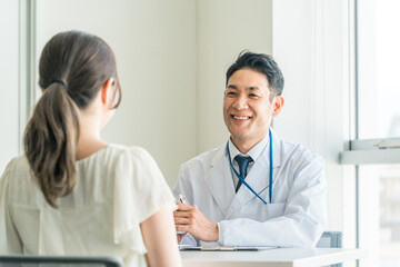 Fototapeta premium 診察・診療・問診・カウンセリングをする医者・医師・ドクターの男性と女性 