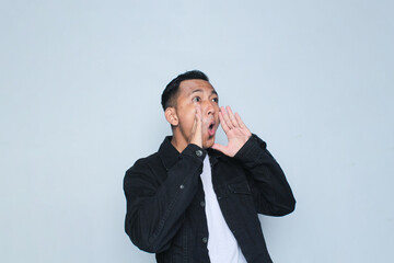 Asian young man wearing black jacket shocking expression on white background.