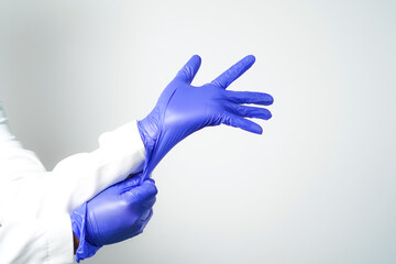 Two hands of a man wearing nitrile purple gloves on a white background