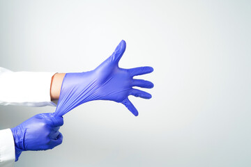 Two hands of a man wearing nitrile purple gloves on a white background