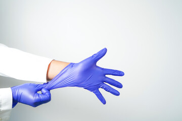 Two hands of a man wearing nitrile purple gloves on a white background