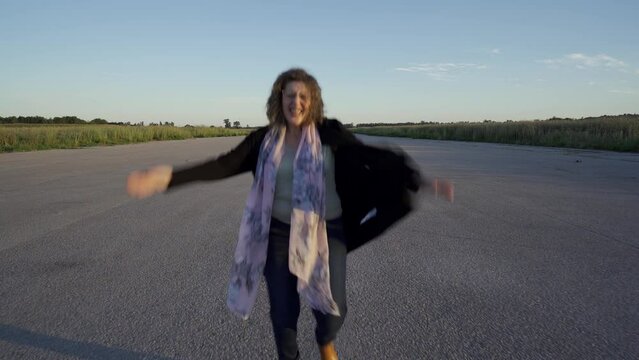 Mujer muy contenta dando saltos de alegr&iacute;a, palmas, y vueltas en una pista de aterrizaje.