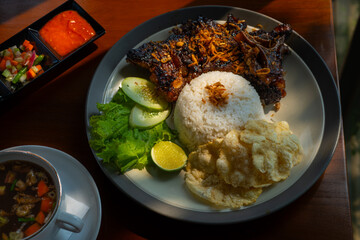 Buntut sapi bakar indonesian dish, or grilled oxtail, served with rice, soup, and sambal chili sauce. Served on wooden table surface