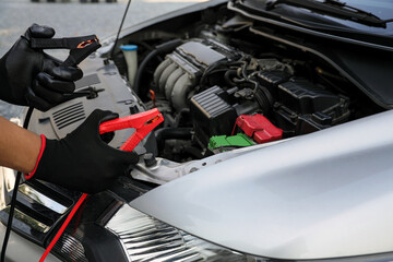 Fototapeta premium Hand car mechanic holding car booster cables for jump start car for empty battery dead and low voltage power problem or fix and service maintenance accident assistance engine doesn't start.