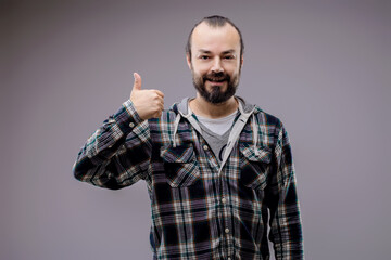 Bearded man with green and black plaid shirt showing thumbs up