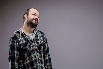 Obraz premium Young bearded man looking up and smiling on grey background