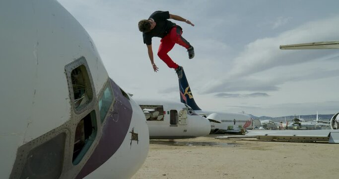 Epic parkour athlete jumping off airplanes in air graveyard - steady cam