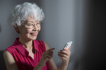 Image of an elderly Asiatic looking with a smartphone