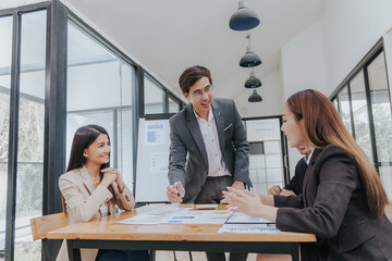 diverse team of professionals, including men and women, engages in a lively discussion. They brainstorm marketing strategies, analyze finance reports, and plan investments for their startup.