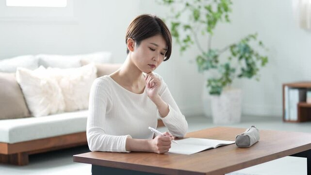 自宅で考えながら学習をする女性