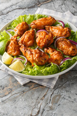 Thai Tom Yum Chicken served with onion, lime and lettuce closeup on the plate on the table. Vertical
