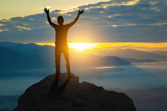 Person silhouette with a prosthetic leg stands on a mountaintop with his arms raised challenge. Freedom healthcare concept, International Disability Day.