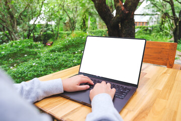 Mockup image of a woman using and typing on laptop computer with blank white desktop screen in the...