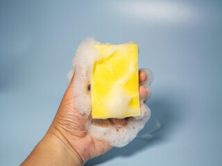 Hand holding foamy cleaning sponge
