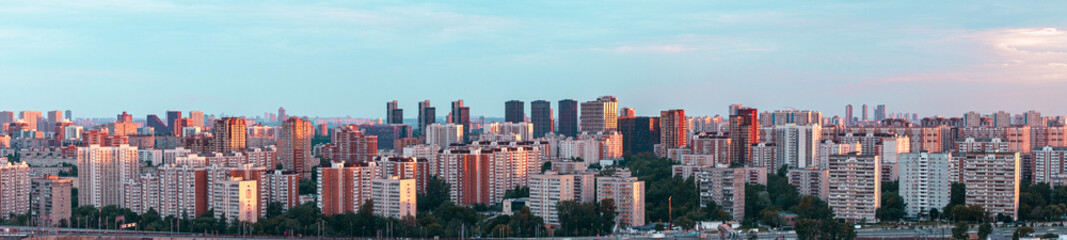 Fototapeta premium Panorama of a big city at sunset from above. Multi-storey buildings in the Khovrino district, Moscow. Selected focus. A place to copy a space.