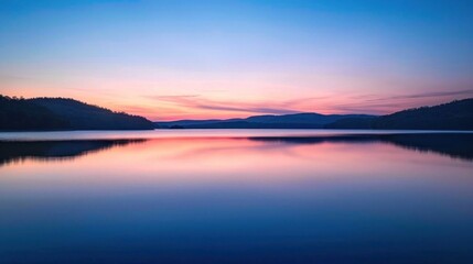 Fototapeta premium A peaceful scene of a calm lake at sunset, with the water reflecting the colors of the sky.