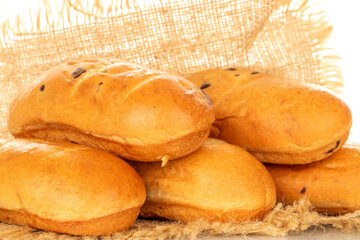 Several fragrant sweet buns on a jute napkin, macro, isolated on a white background.