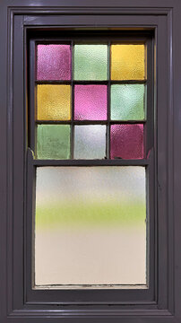 old single hung window with colorful stained glass on grey painted timber frame