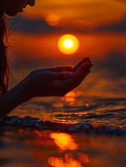 A woman praying in the water at sunset.