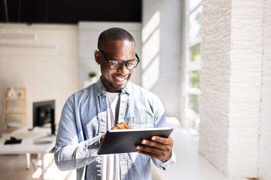African businessman in black suit using digital tablet in busy market